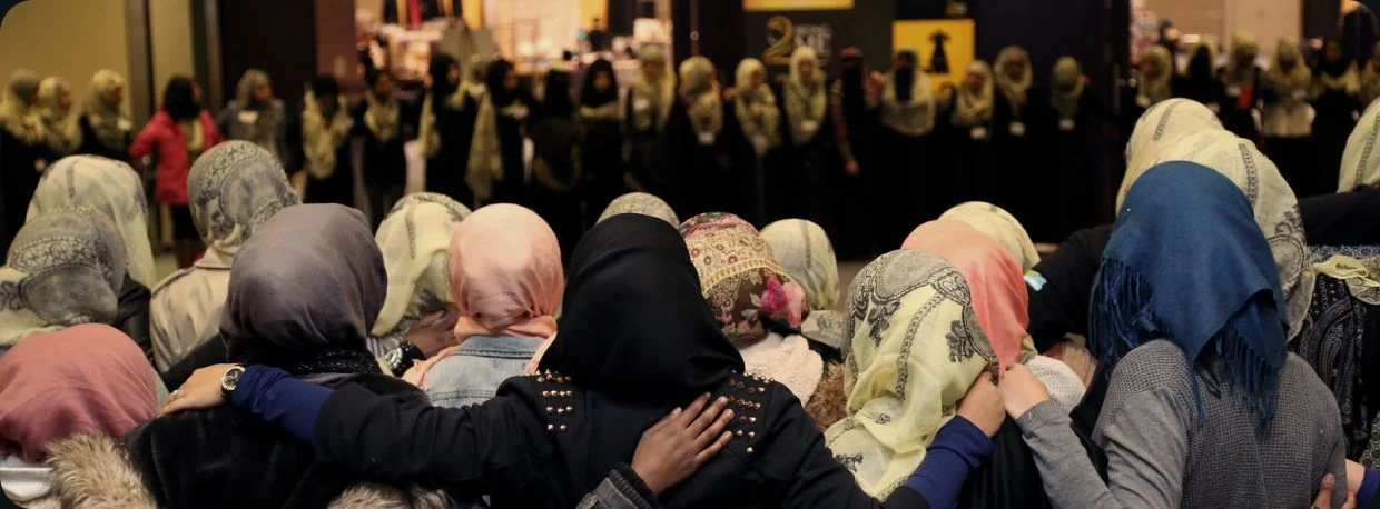 Women standing shoulder to shoulder with arms around each other at a Being ME conference
